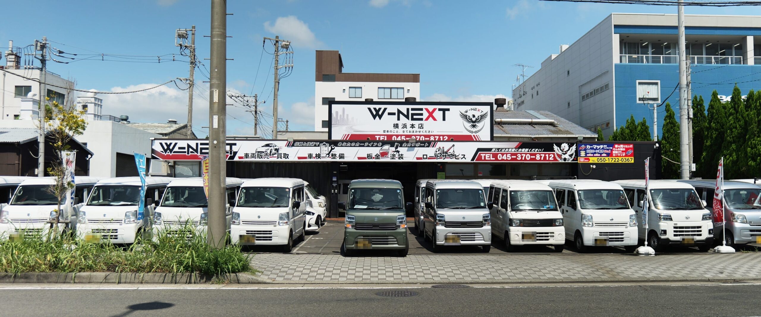 W-NEXT横浜本店の店頭に並ぶ軽バンと新しい看板