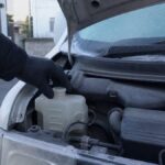 冷却水のタンクを確かめる整備士の手元